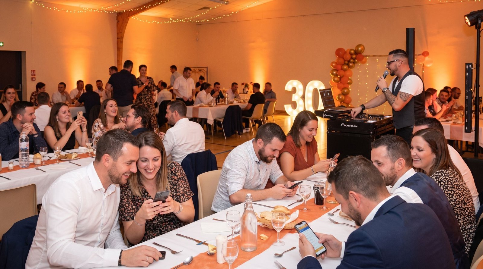Invités attablés qui jouent au quiz sur leur smartphone, Joël R'Key au micro derrière sa régie
