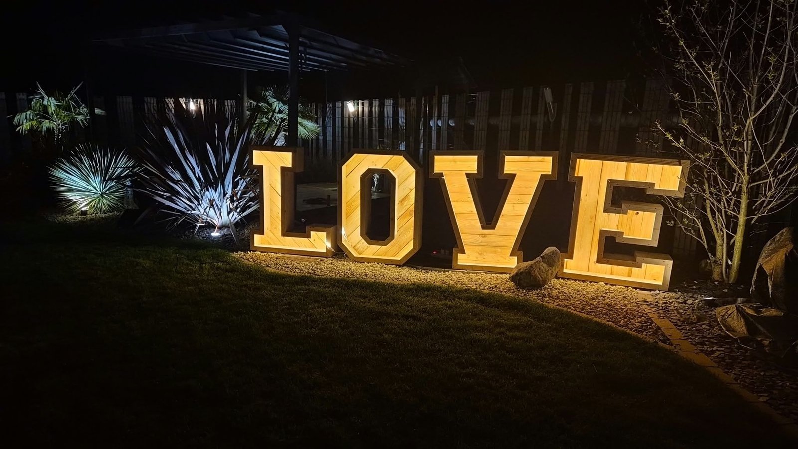 Lettres géantes LOVE lumineuses la nuit, sur la pelouse